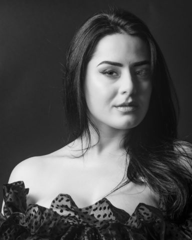Black-and-white close studio portrait of a woman with direct gaze and dark clothing, from Beauty — Studio Studies I by Jonathan B. Landman.